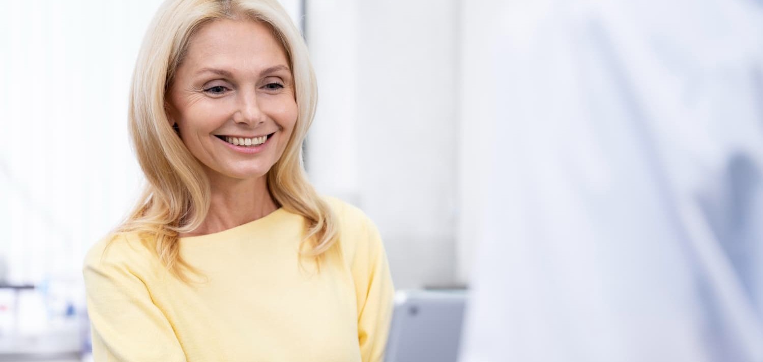 Middle-aged woman in a clinic, smiling during a consultation